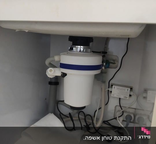 מתקן טוחן אשפה מתחת לכיור עם צינורות וחוטים
